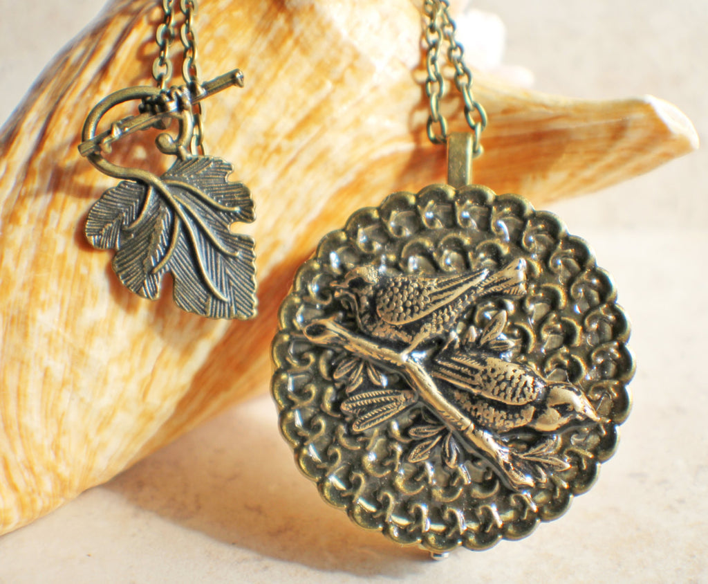 Music box locket, round bronze locket with music box inside, with a bronze filigree and a bronze birds on front cover. - Char's Favorite Things - 1